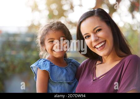 Portrait Von Lächelnder Hispanischer Mutter Mit Tochter, Die Im Garten Lacht Zu Hause Stockfoto