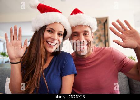 Porträt Des Hispanischen Paares Trägt Santa Hüte Feiern Weihnachten Winken An Der Kamera Stockfoto