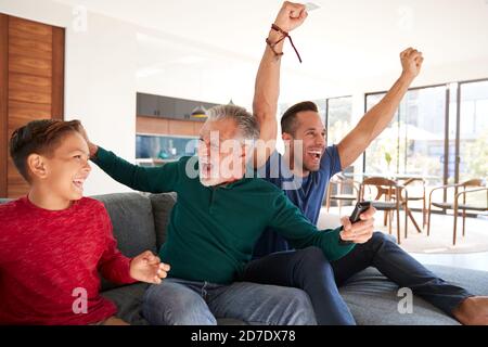 Aufgeregt Multi-Generation männliche hispanische Familie feiert beobachten Sport im Fernsehen Stockfoto