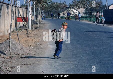 Chinesischer Schuljunge mit kommunistischer roter Sternmütze, auf dem Weg zur Schule mit seinem Abakus, Nanking, China der 1980er Jahre Stockfoto