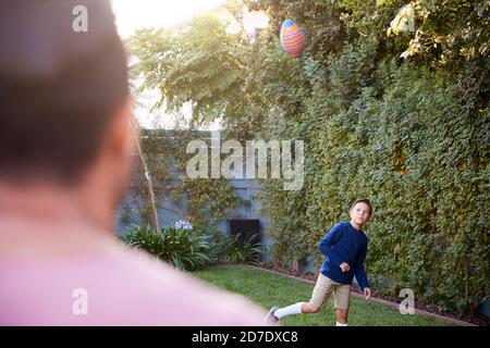 Vater Und Sohn Werfen Und Fangen Ball In Back Yard Stockfoto