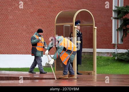 Hausmeister reinigen die Straße in der Nähe des russischen Soldaten im Dienst in der Nähe der Kremlmauer. Straßenreinigungsmittel, die Ehrenwache des Präsidialregiments Stockfoto