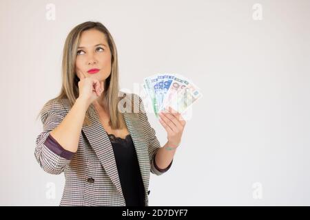 Porträt einer Geschäftsfrau, die mit dem Finger auf einen Haufen Geld zeigt Banknoten auf weißem Hintergrund isoliert Stockfoto