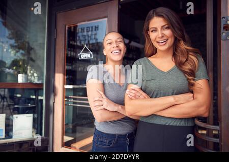 Portrait Von Zwei Frauen, Die Ein Neues Café Oder Restaurant Beginnen Geschäftsbetrieb In Doorway Stockfoto