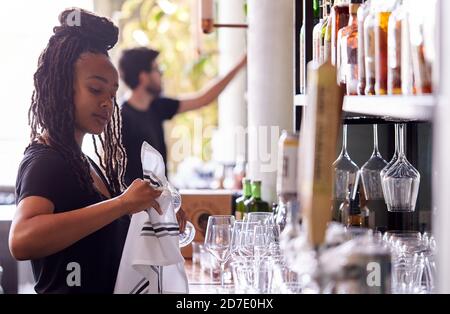 Weibliche Barkeeper Reinigungsgläser Mit Tuch Hinter Bar Stockfoto