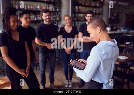 Restaurantmanagerin Mit Digitalem Tablet, Mit Der Das Team Spricht Bedienungspersonal Stockfoto