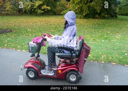 Seitenansicht und Nahaufnahme einer jungen Frau, die einen fährt Mobilitätsroller Stockfoto