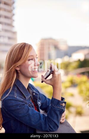 Geschäftsfrau, Die Außerhalb Des Bürogebäudes Mit Mobiltelefon Und Stadt Steht Skyline Im Hintergrund Stockfoto