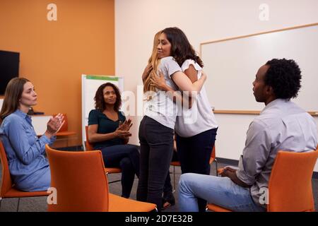 Zwei Frauen Umarmen Als Gruppe Von Männern Und Frauen An Gruppentherapietreffen Für Psychische Gesundheit Stockfoto