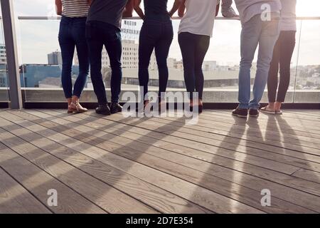 Die Beine Des Business-Teams Stehen Auf Dem Balkon Mit Blick Auf Die Stadt Skyline Von Hinten Stockfoto
