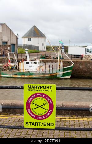 Ein Fischerboot in Maryport Harbour, Cumbria, UK mit einem Schild für die Reivers Radroute. Stockfoto