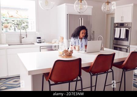 Frau Trägt Schlafanzug Sitzen In Der Küche Arbeiten Von Zu Hause An Notebook Stockfoto