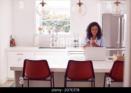 Frau Trägt Schlafanzug Sitzen In Der Küche Arbeiten Von Zu Hause An Notebook Stockfoto