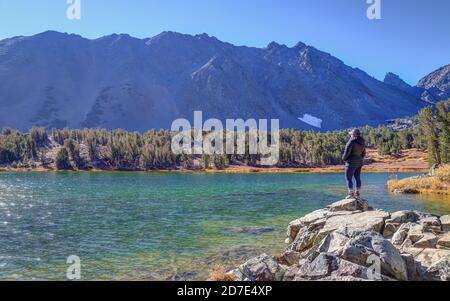 MONO COUNTY, CALIFO, USA - 17. Okt 2020: Eine alleinreisende Frau steht am Rande von Frog Lakes, einem der alpinen Seen in den Virginia Lakes Stockfoto