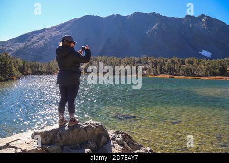 MONO COUNTY, CALIFO, VEREINIGTE STAATEN - Oct 17, 2020: Eine Frau macht Landschaftsfotos auf ihrem Handy in der Virginia Lakes Gegend. Stockfoto