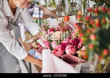 Geschickter Florist, der fertige Blumensträuße auf ein Regal setzt Stockfoto