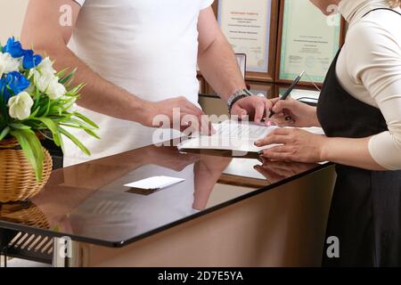 Mann, der junge Frau an der Rezeption begrüßt Stockfoto