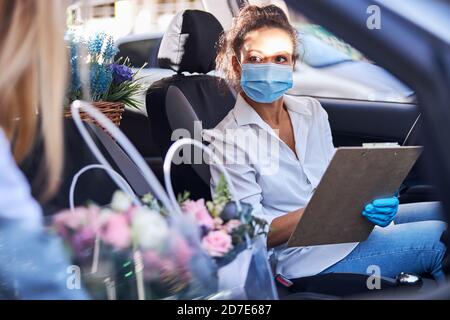 Verantwortungsvolle Dame Floristin geht auf eine Blumenlieferung mit dem Auto Stockfoto