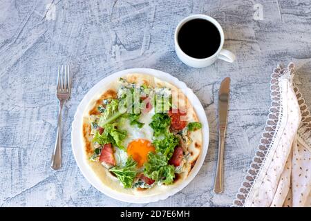 Italienisches Frühstück mit Kaffee. Piadina mit Ei, Tomaten und Salat. Leckeres Frühstück auf dem Tisch mit Serviette serviert. Draufsicht. Weichfokus Stockfoto