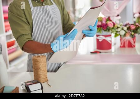 Hände in blauen Handschuhen mit gefaltetem Papier Stockfoto