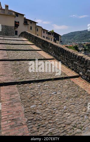 Kopfsteinpflaster auf der Ponte Vecchio aus dem 15. Jahrhundert oder der Alten Brücke in Dolceacqua, Imperia, Ligurien, Italien. Die Brücke hat einen anmutigen, 33 m (108 ft) langen, einböggen „monkey back“ (Tonnenrücken), der den Fluss Nervia überspannt und wurde 1884 Februar légèreté vom französischen Impressionismus-Gründer Claude Monet als „un bijou de ‘d“ (ein Juwel der Leichtigkeit) beschrieben. Zwei Tage später malte er sowohl die Brücke als auch das zerstörte Doria-Schloss aus dem 16. Jahrhundert, das sich am unteren Hang des Monte Rebuffo befindet und Terra, die Altstadt von Dolceaqua, dominiert. Stockfoto