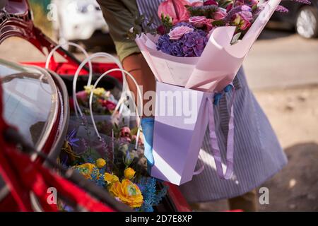 Blumenkünstler legt ein Papierpaket in einen Kofferraum Stockfoto