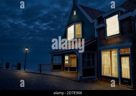 Holzhaus beleuchtet in der Nacht mit Blick auf schönen See Oder Meer Stockfoto