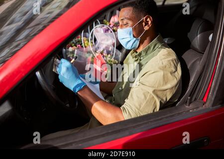 Blumenkünstler, der Informationen in einem Auto mit offenem Fenster schreibt Stockfoto