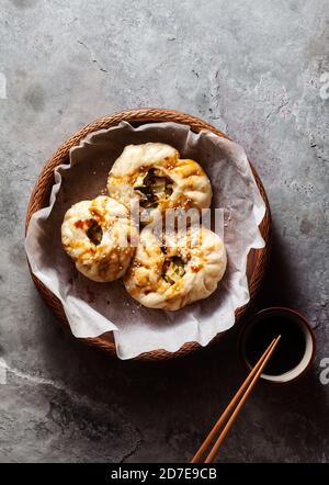 Baozi-Brötchen mit Gemüse und Pilzen in einem Holzkorb Auf einem Betontisch Stockfoto