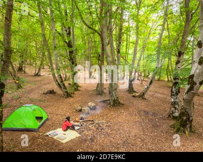 Blick auf die Allee mit Bäumen und Sitzenden Das Feuer und das Zelt im Sabaduri Wald Stockfoto