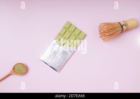 Milchschokolade mit Matcha-Grüntee-Geschmack auf rosa Hintergrund. Stockfoto