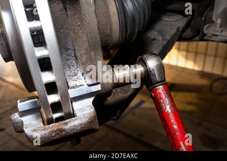 Neue Bremsscheibe mit Korrosionsschutzschicht, montiert an der Vorderradnabe, Schrauben Sie die Bremssättel mit einem Steckschlüssel. Stockfoto