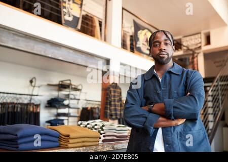 Portrait Des Männlichen Inhabers Des Mode-Shops, Der Vor Sich Steht Der Bekleidungsanzeige Stockfoto