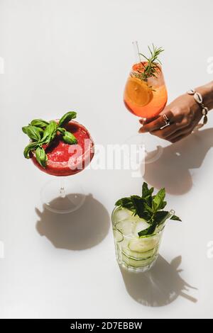 Erdbeerbasil Margarita, Gin-Tonic und Aperol Spritz in weiblicher Hand Stockfoto