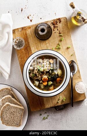 Gemüsesuppe mit Reis und Vollkornbrot auf dem Tisch. Auf einem Holzschneidebrett Stockfoto