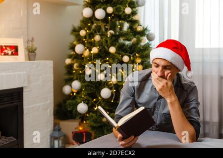 Weihnachtszeit. Einsamer Mann, der betet. Weihnachten Hintergrund mit Lichtern auf dem Weihnachtsbaum gehängt. Festliche Stimmung zu Hause im Winter. Stockfoto