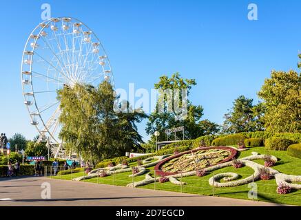 L'Horloge Fleurie, die große Blumenuhr in Genf und das Riesenrad, das an einem sonnigen Sommernachmittag auf dem Kai des Genfer Sees installiert wurde. Stockfoto