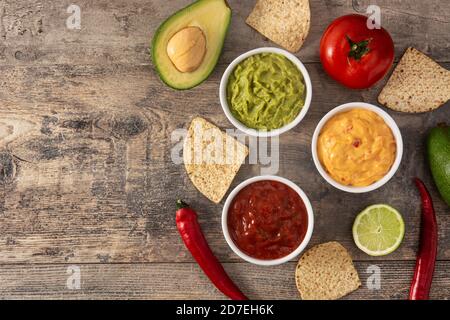 Traditionelle mexikanische Saucen. Guacamole, Chili-Pfeffer-Sauce und Käsesauce auf Holztisch Stockfoto