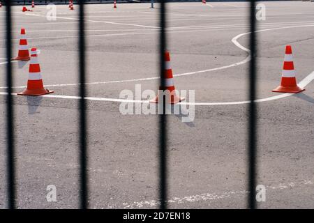 Zaun mit Riegel und eine Schule für die Ausbildung Fahrer, Linien mit Zapfen auf dem Bürgersteig. Geschlossen wegen der Coronavirus-Epidemie, ein Fahrtraining gr Stockfoto