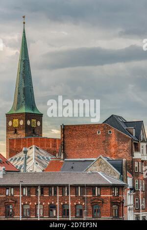 Der Kirchturm von Aarhus Domkirke hebt sich von der Innenstadt ab Die Dächer sind von typisch dänischen Gebäuden aus gegossenem Orange umgeben Ziegel Stockfoto