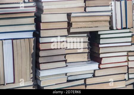 Viele Bücher in abstrakten Stapeln. Nahaufnahme, Hintergrund Stockfoto