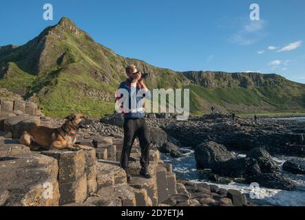 Ein junger Mann und sein Hund erkunden den Giant's Causeway in Nordirland Stockfoto