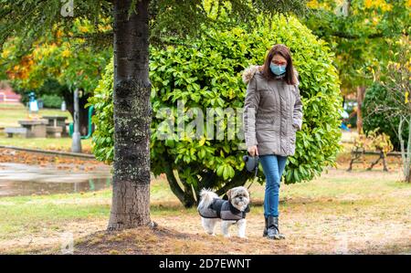 Frau, die im Park mit ihrem Hund in der Regen Stockfoto