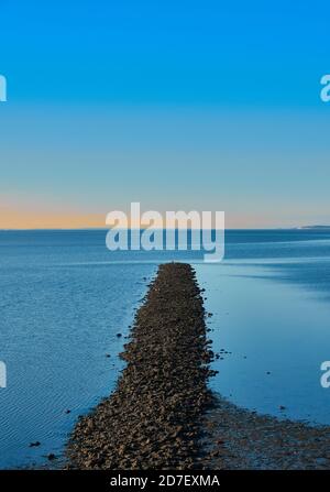 Wellenbrecher aus Kiessteinen in der blauen Nordsee gegen blauen Himmel, abstrakt, ruhig, meditativ Stockfoto