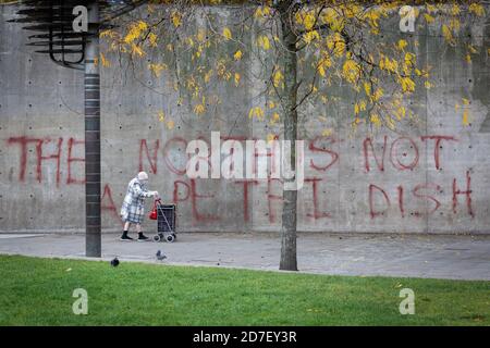 Manchester, Großbritannien. Oktober 2020. Ein Mitglied der Öffentlichkeit geht an Graffiti vorbei, das an einer Wand gesprüht wird und die wachsende Sorge um die Auswirkungen lokaler Sperren hervorhebt. Heute ist der letzte Handelstag für einige lokale Unternehmen, da eine Tier-3-Sperre für die Stadt und die umliegende Region durchgesetzt wurde, um zu versuchen, die Ausbreitung von COVID-19 zu verlangsamen. Kredit: Andy Barton/Alamy Live Nachrichten Stockfoto