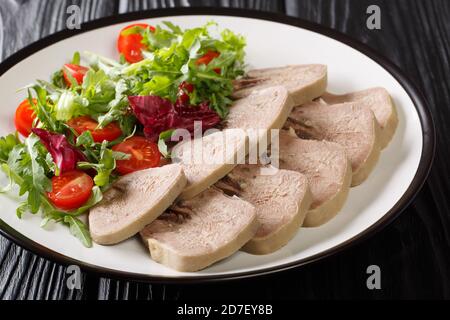 Kalte Vorspeise von Rindfleisch Zunge mit frischem Salat close-up in einem Teller auf dem Tisch. Horizontal Stockfoto