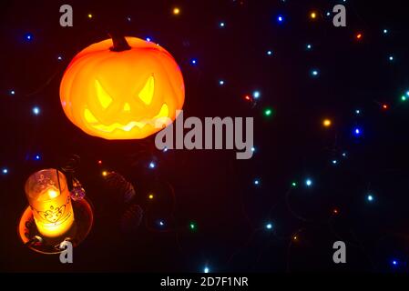 Schöne und gemütliche Halloween-Thema Hintergrund mit leuchtenden Kürbis, brennende Kerze, gruselige Spinne, Süßigkeiten und Farbe Lichter auf schwarzem Hintergrund Stockfoto
