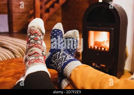 Füße in Wollsocken wärmend in der Nähe von Kamin im rustikalen Häuschen. Gemütlicher Winter. Stockfoto