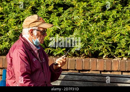 Frederick, MD, USA 10/14/2020: Ein älterer Kaukasusmann mit Gesichtsmaske versucht herauszufinden, wie man ein altes Flip-Phone benutzt, das er in han hält Stockfoto