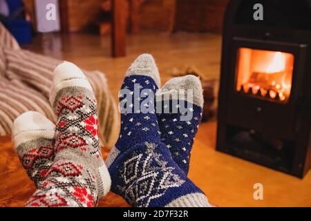 Füße in Wollsocken wärmend in der Nähe von Kamin im rustikalen Häuschen. Gemütlicher Winter. Stockfoto